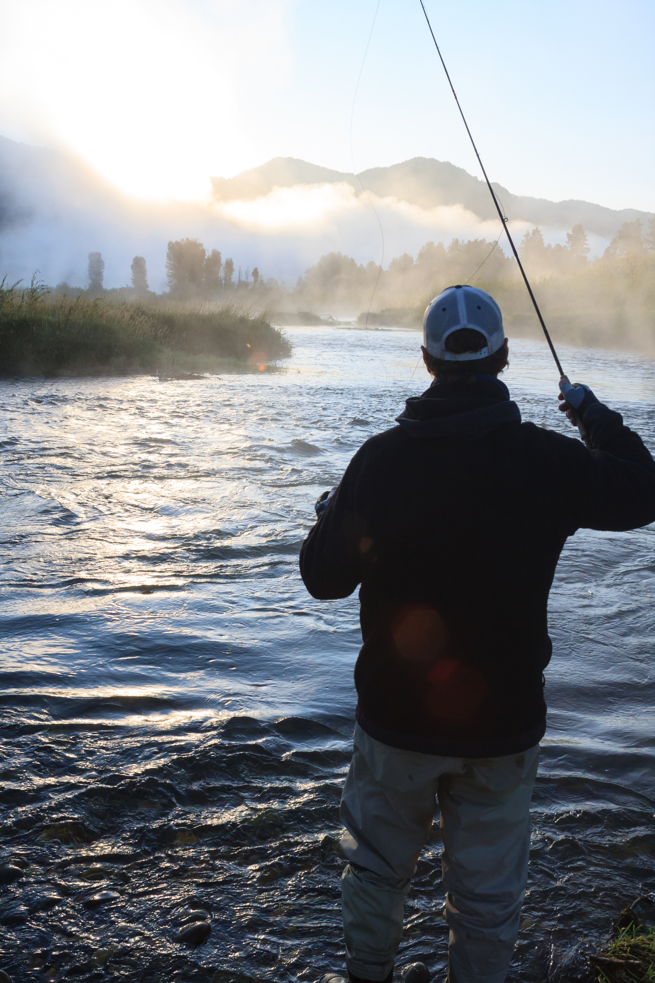 Fly fisherman casting on the Snake River at sunrise